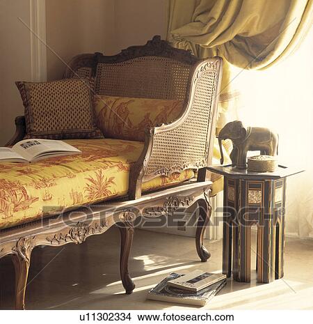 Picture - Upholstered antique bergere chaiselongue in traditional living room. Fotosearch