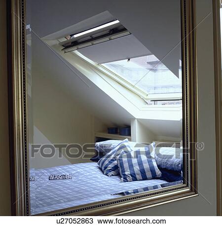 Velux window above blue check cushions and linen on bed in loft conversion bedroom reflected in mirror View Large Photo Image Stock Image - Velux window above blue check cushions and linen on bed in loft conversion bedroom reflected in mirror. Fotosearch