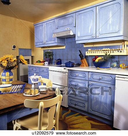 Vernice, effetto, afflitto, blu, andato bene, credenze, in, giallo, cucina, con, tavola legno, e, giallo, sedie Archivio Fotografico Vernice, effetto, afflitto, blu, andato bene, credenze, in, giallo, cucina, con, tavola legno, e, giallo, sedie Archivio Fotografico