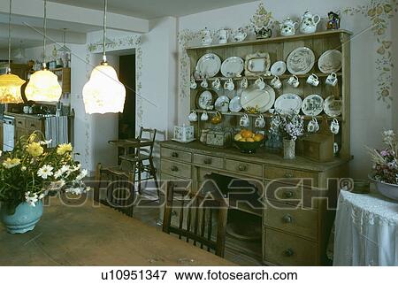 Stock Photo - Victorian glass lights above table in traditional kitchen with antique pine dresser. Fotosearch