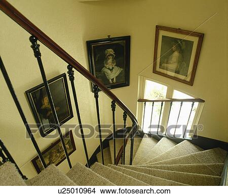 Picture - Victorian pictures on wall above curved staircase with security railings on window and cream carpet. Fotosearch