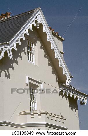 White bargeboarding on gable above windows in beige Victorian house View Large Photo Image Stock Photo - White bargeboarding on gable above windows in beige Victorian house. Fotosearch