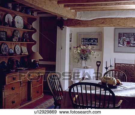 White cloth on small circular table in beamed cottage dining room with dresser and Windsor chairs at dining table View Large Photo Image Stock Photo - White cloth on small circular table in beamed cottage dining room with dresser and Windsor chairs at dining table. Fotosearch