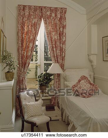 White cover on single bed in guest toom with patterned red curtains at glass doors and small upholstered chair View Large Photo Image Stock Image - White cover on single bed in guest toom with patterned red curtains at glass doors and small upholstered chair. Fotosearch
