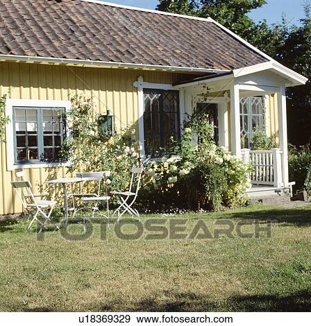 White furniture on lawn in front of single-storey pastel yellow cottage with white porch View Large Photo Image Stock Photo - White furniture on lawn in front of single-storey pastel yellow cottage with white porch. Fotosearch