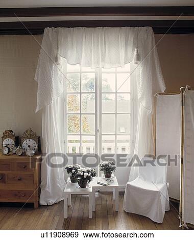 White Loosecover On Chair In Front Of French Windows With White Loosecover On Chair In Front Of French Windows With