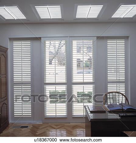 Stock Image - White louvred doors in modern study. Fotosearch