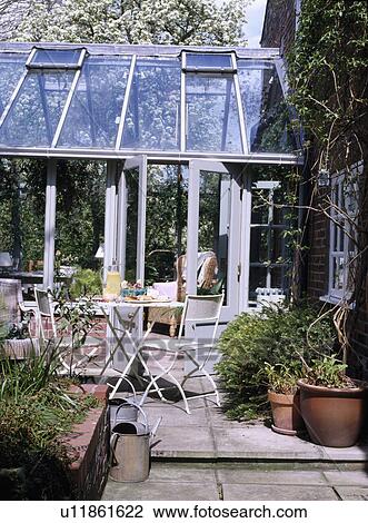 White metal furniture on patio in front of glass conservatory extension View Large Photo Image Stock Image - White metal furniture on patio in front of glass conservatory extension. Fotosearch