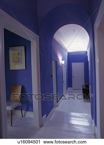 Stock Image - White painted floorboards in narrow blue hall with white doors. Fotosearch