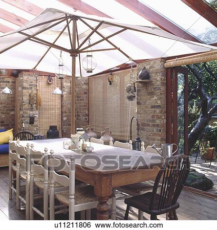 White parasol above old pine table with rush seated chairs in conservatory dining room View Large Photo Image Stock Photograph - White parasol above old pine table with rush seated chairs in conservatory dining room. Fotosearch