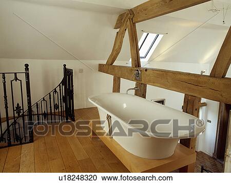 White Rolltop Bath On Platform Beside Large Open Beams In Modern