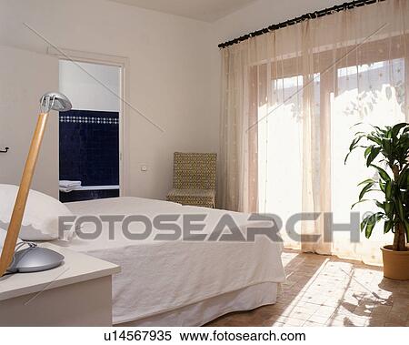 White scheme with voile curtains for this modern bedroom with bathroom ensuite. View Large Photo Image Stock Photography - White scheme with voile curtains for this modern bedroom with bathroom ensuite.. Fotosearch