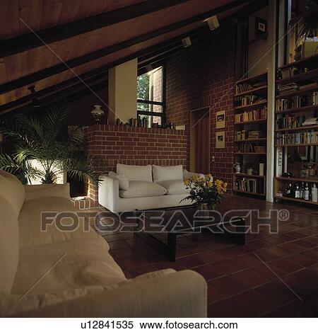 White sofa against brick wall in eighties-style living room with terracotta tiled floor View Large Photo Image Stock Photography - White sofa against brick wall in eighties-style living room with terracotta tiled floor. Fotosearch