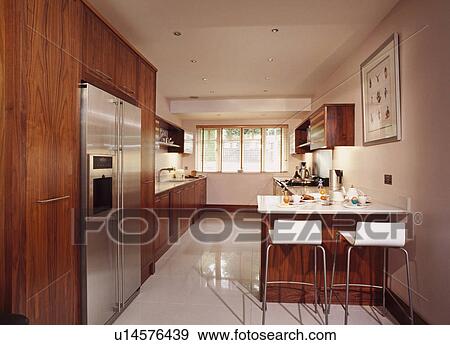 White stools at breakfast bar in modern kitchen with American style fridge freezer and white floor tiles View Large Photo Image Stock Photo - White stools at breakfast bar in modern kitchen with American style fridge freezer and white floor tiles. Fotosearch