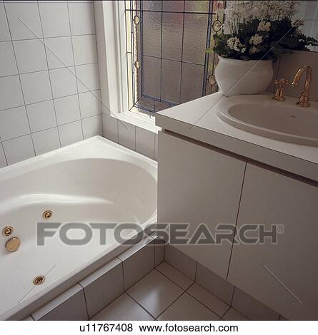 Stock Photo - White tiled architectural bathroom with brass fittings.. Fotosearch