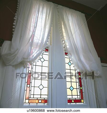 Stock Photo - White voile curtains at tall stained glass windows. Fotosearch