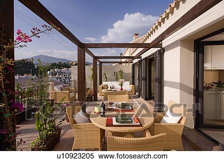 Stock Photography - Wicker furniture on large balcony of Spanish holiday apartment with view of mountains. Fotosearch