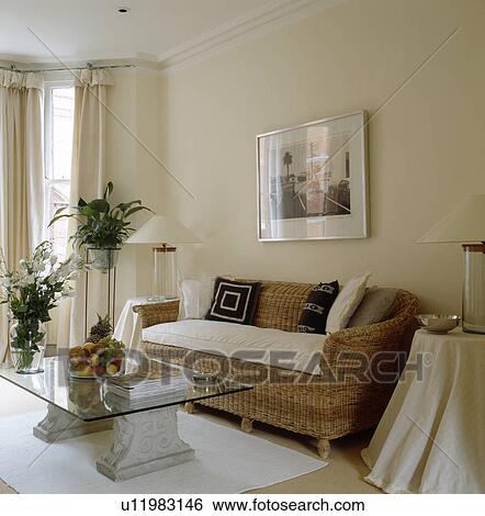 Stock Photograph - Wicker sofa and glass & stone table in modern cream living room. Fotosearch