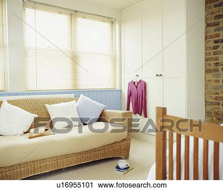 Wicker sofa in a blue and white bedroom with exposed brickwork under the eaves of a contemporary attic conversion View Large Photo Image Stock Image - Wicker sofa in a blue and white bedroom with exposed brickwork under the eaves of a contemporary attic conversion. Fotosearch