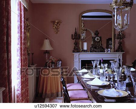 Stock Photo - Wine glasses and place settings on table in dark pink traditional dining room . Fotosearch