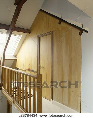 Picture - Wooden bannisters on narrow attic landing with door in wood wall. Fotosearch
