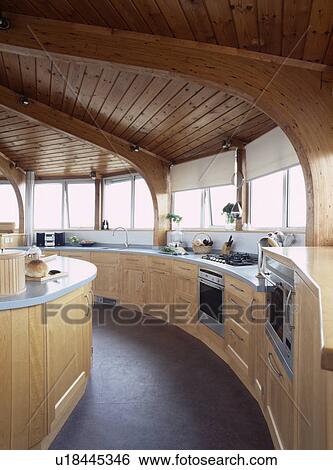 Stock Photograph - Wooden ceiling in circular pale wood modern kitchen with slate flooring. Fotosearch