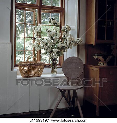 Wooden chair in front of tall casement window with basket and white flowers in vase on windowsill View Large Photo Image Stock Photo - Wooden chair in front of tall casement window with basket and white flowers in vase on windowsill. Fotosearch