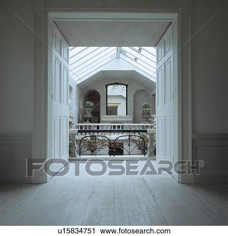 Stock Image - Wooden floorboards in large empty room with view through double doors of Georgian landing. Fotosearch