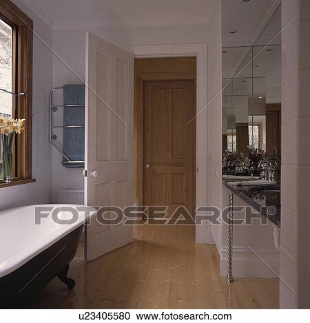 Wooden flooring and rolltop bath in modern white bathroom with door open to landing View Large Photo Image Stock Image - Wooden flooring and rolltop bath in modern white bathroom with door open to landing. Fotosearch