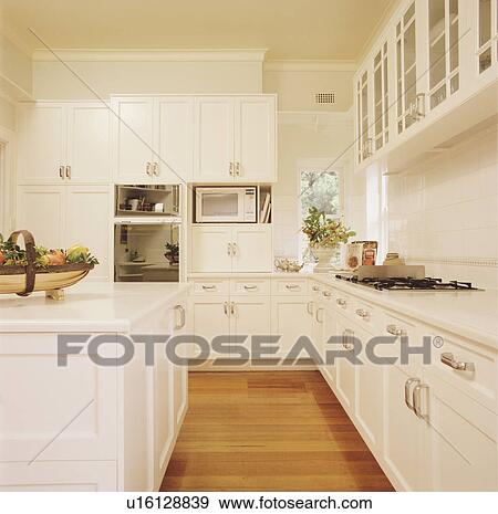 Wooden flooring in large white kitchen with painted wood fitted cupboards View Large Photo Image Stock Photo - Wooden flooring in large white kitchen with painted wood fitted cupboards. Fotosearch