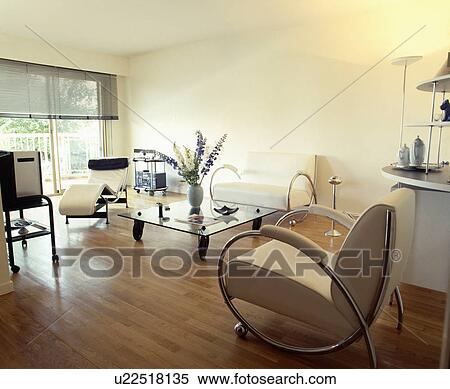 Stock Photography - Wooden flooring in modern living room with chrome and leather chair and glass table. Fotosearch