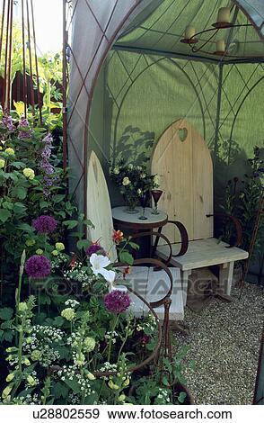 Stock Photo - Wooden Gothic chairs in gazebo in small garden in summer. Fotosearch