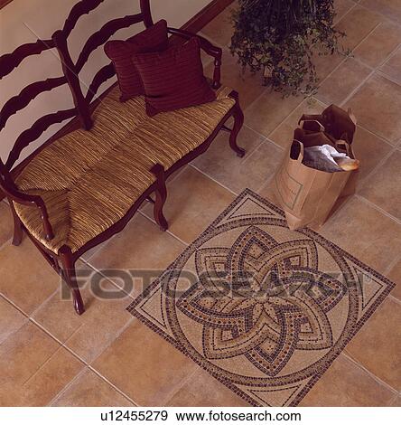 Stock Photo - Wooden settle with rush seat on floor with ornate mosaic pattern on tiled floor. Fotosearch