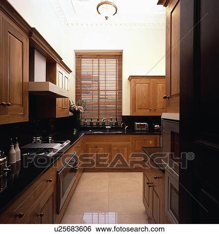 Wooden slatted blind in modern kitchen with limestone flooring and black granite worktops View Large Photo Image Stock Photograph - Wooden slatted blind in modern kitchen with limestone flooring and black granite worktops. Fotosearch