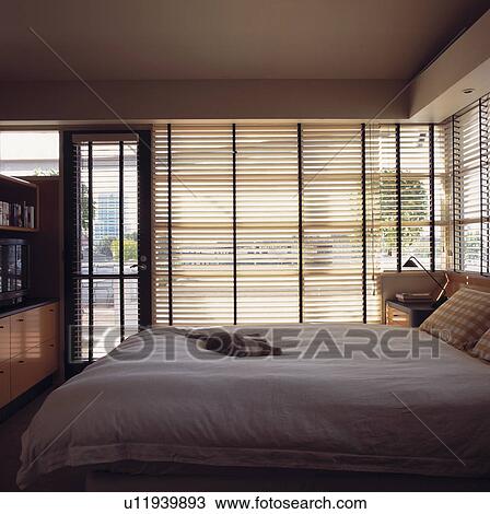 Wooden Slatted Blinds On Large Window In Modern Bedroom With Cat Asleep On White Duvet Stock Image