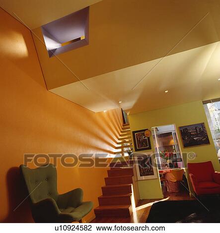 Wooden staircase in large openplan modern orange and yellow hall and living room View Large Photo Image Stock Image - Wooden staircase in large openplan modern orange and yellow hall and living room . Fotosearch