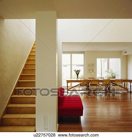 Wooden staircase in modern openplan hall and dining room with wooden flooring and red sofa View Large Photo Image Stock Photo - Wooden staircase in modern openplan hall and dining room with wooden flooring and red sofa. Fotosearch