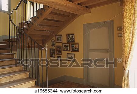 Picture - Wooden staircase in traditional hall with pastel yellow walls and grey paintwork. Fotosearch