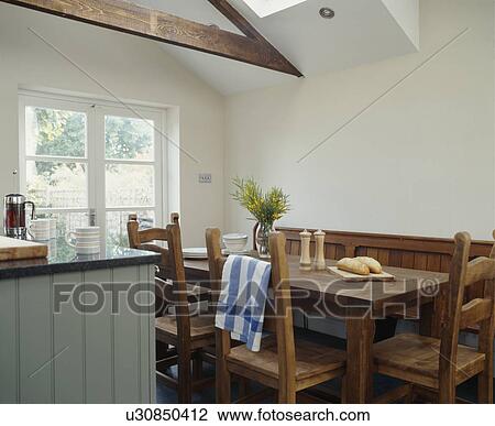 Wooden table and chairs in white dining room extension with apex ceiling View Large Photo Image Stock Image - Wooden table and chairs in white dining room extension with apex ceiling. Fotosearch