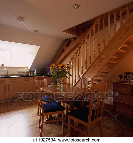 Wooden table and chairs with blue seats in front of wooden stairs in modern attic kitchen View Large Photo Image Picture - Wooden table and chairs with blue seats in front of wooden stairs in modern attic kitchen. Fotosearch