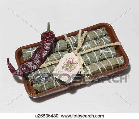 Stock Image - Wrapped herb bundles in brown earthenware dish. Fotosearch