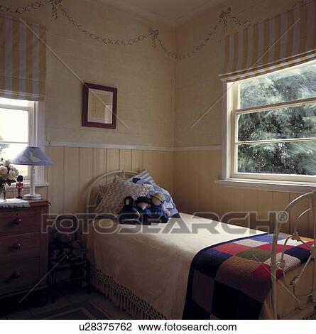 Yellow striped blinds on windows above single white iron bed with blue+white cushions and knitted patchwork throw View Large Photo Image Stock Image - Yellow striped blinds on windows above single white iron bed with blue+white cushions and knitted patchwork throw. Fotosearch
