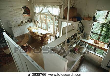 Stock Photograph - Aerial view of dining room and kitchen in garage conversion divided by shelf unit with sink and oven . Fotosearch