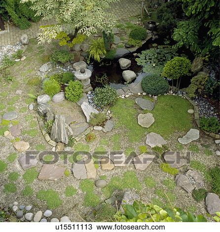 Stock Image - Aerial view of paving stones and small water feature in Japanese-style garden. Fotosearch