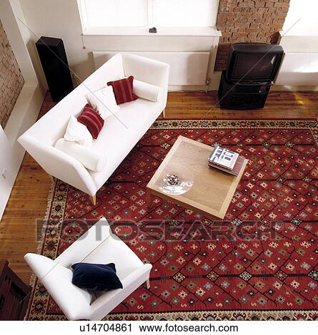 Stock Image - Aerial view of white sofa in modern living room with large patterned red oriental rug. Fotosearch