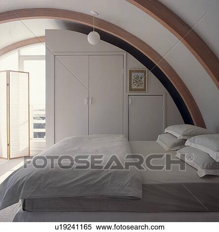 Stock Photography - All white architectural bedroom with curved laminated beams.. Fotosearch