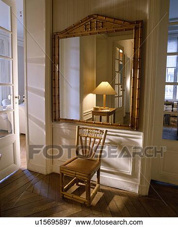 Antique bamboo mirror above bamboo chair in white hall with reflection of lamp in mirror View Large Photo Image Stock Photo - Antique bamboo mirror above bamboo chair in white hall with reflection of lamp in mirror. Fotosearch