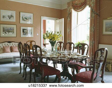 Stock Photo - Antique chairs and table in neutral dining room with swagged curtains. Fotosearch