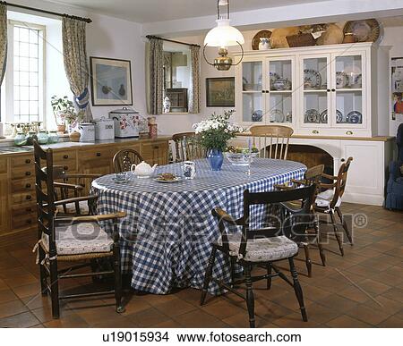 Antique chairs around table with blue and white checked PVC cloth in country kitchen with white dresser View Large Photo Image Picture - Antique chairs around table with blue and white checked PVC cloth in country kitchen with white dresser. Fotosearch