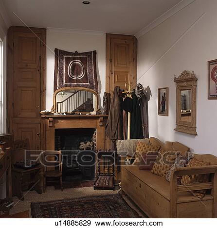 Stock Photo - Antique pine settle in small living room with mirror above pine fireplace and pine doors on alcove cupboards. Fotosearch